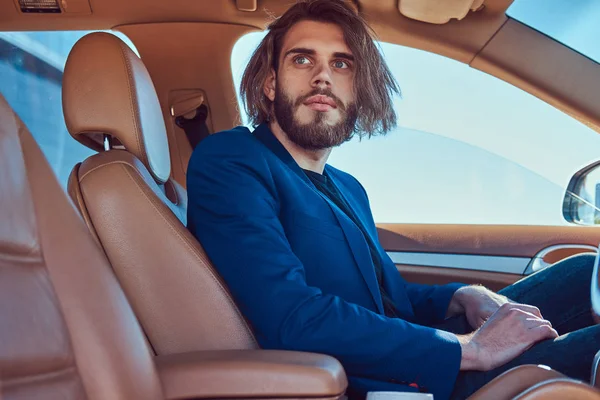 英俊时尚男性与胡子和长的头发坐在豪华车 — 图库照片