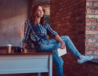 Genç sevimli kız fotoğrafçı bir tablet ile çalışma çatı iç bir stüdyoda bir masada oturur.