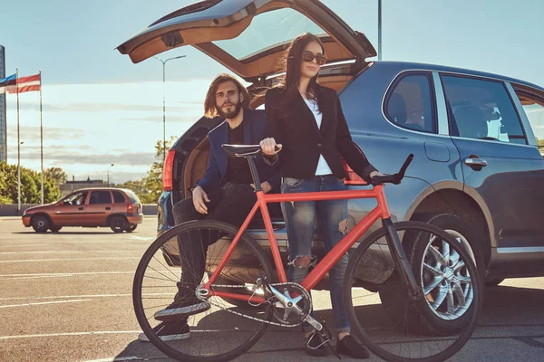 Atractiva Pareja Elegante Con Una Bicicleta Cerca Del Coche Con — Foto de Stock