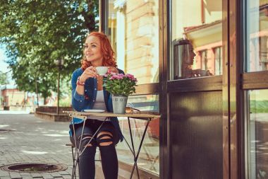 Güzellik Kızıl saçlı kız içecekler kahve, kahve dükkan yakın oturan.