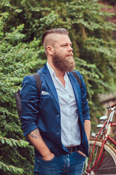 Male dressed in casual clothes, standing with a retro bicycle in a park.