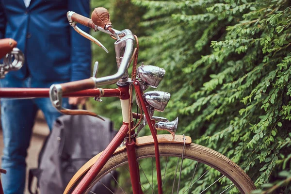 Man gekleed in casual kleding, staande in de buurt van een retro fiets in een park. — Stockfoto