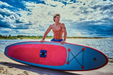 Sörfçü erkek ile kas vücut plaj onun surfboard ile.