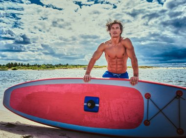 Sörfçü erkek ile kas vücut plaj onun surfboard ile.