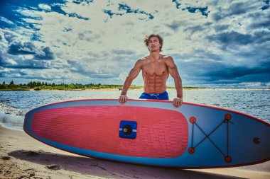 Sörfçü erkek ile kas vücut plaj onun surfboard ile.