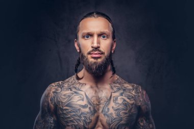 Şık bir saç kesimi, karanlık bir arka plan üzerinde izole kas sakallı tattoed erkekle yakın çekim portresi.