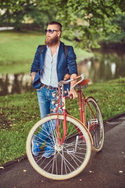 Rahat kıyafetler ve bir sırt çantası, rahatlatıcı bir retro bisiklet sürme sonra bir şehir parkı ile güneş gözlüğü Gezgin giymiş.