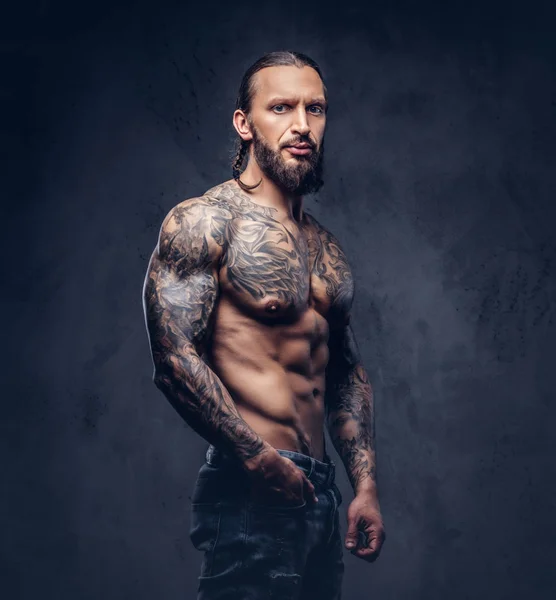 Nahaufnahme eines muskulösen nackten bärtigen, tätowierten Mannes mit stylischem Haarschnitt, isoliert auf dunklem Hintergrund. — Stockfoto