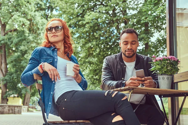 Ett par dating dricka kaffe, sitter nära coffee shop. Utomhus på ett datum. — Stockfoto