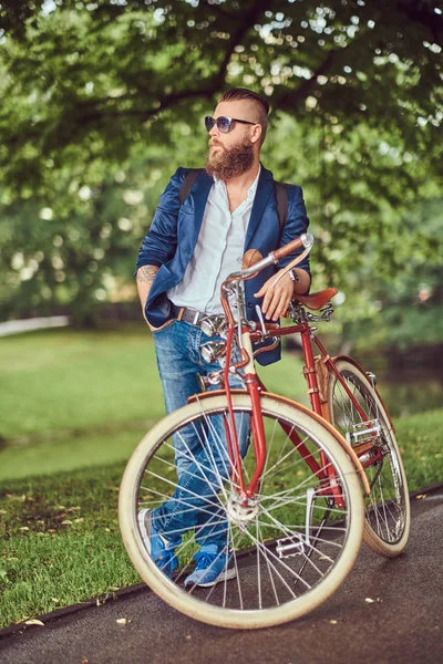 Reiziger gekleed in casual kleding en zonnebrillen met een rugzak, ontspannen in een stadspark na het rijden op een retro fiets. — Stockfoto