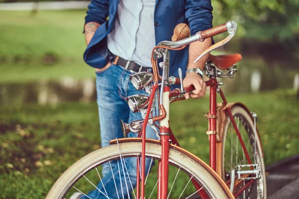 Reisender in lässiger Kleidung mit Rucksack, der sich nach einer Fahrt mit einem Retro-Fahrrad in einem Stadtpark entspannen will. — Stockfoto