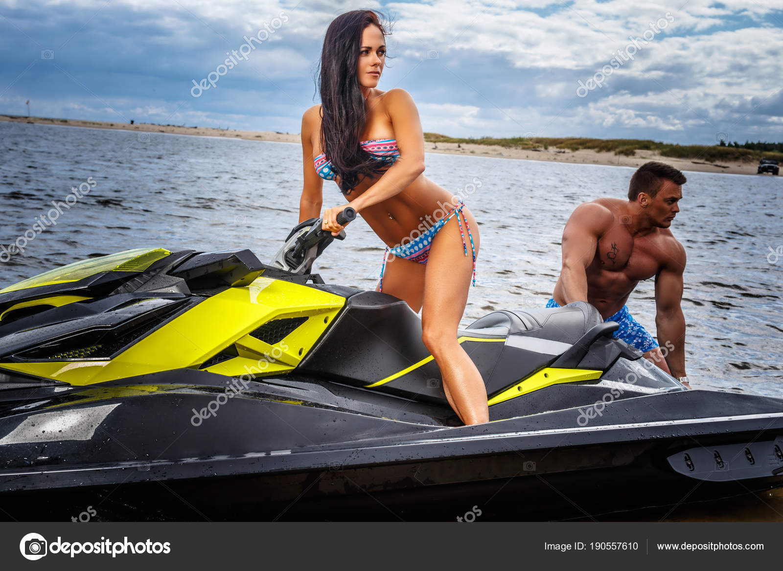 Attractive couple of a sexy girl and shirtless muscular male have fun with  a jet ski on a seacoast. Stock Photo by ©fxquadro 190557610