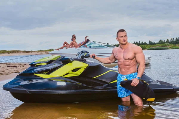 Beau sportif torse nu avec un corps musclé debout près du jet ski sur une côte . — Photo