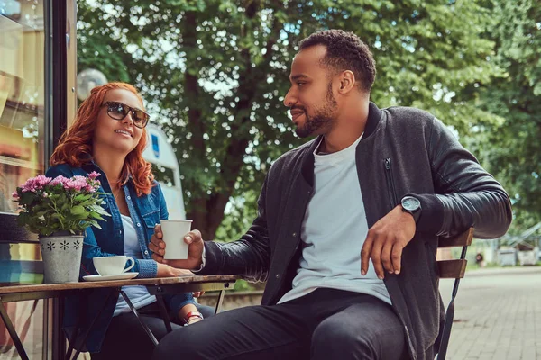 Um casal a beber café, sentado perto do café. Ao ar livre em uma data . — Fotografia de Stock