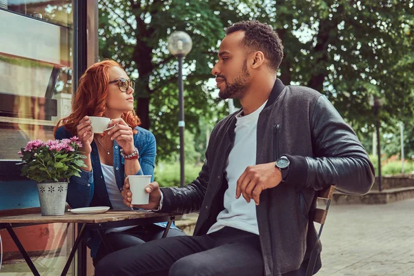 Um casal a beber café, sentado perto do café. Ao ar livre em uma data . — Fotografia de Stock