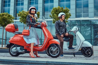 Çekici Romantik Çift, yakışıklı ve seksi erkek, bir gökdelen karşı retro İtalyan scooter üzerinde oturan.