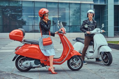 Çekici Romantik Çift, yakışıklı ve seksi erkek bir gökdelen karşı retro İtalyan scooter üzerinde oturuyor. Telefonla konuşurken kız süre bekleyen bir adam.