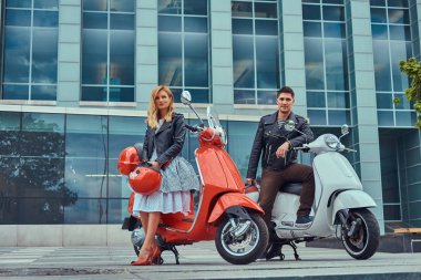 Çekici Romantik Çift, yakışıklı ve seksi erkek, bir gökdelen karşı iki retro İtalyan scooter ile ayakta.