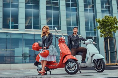 Çekici Romantik Çift, yakışıklı ve seksi erkek, bir gökdelen karşı iki retro İtalyan scooter ile ayakta.