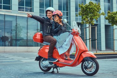 Çekici mutlu çift, yakışıklı ve seksi erkek birlikte bir şehirde kırmızı bir retro scooter sürme.