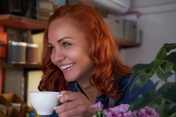 Eine rothaarige Barista trinkt einen Kaffee im Café. — Stockfoto