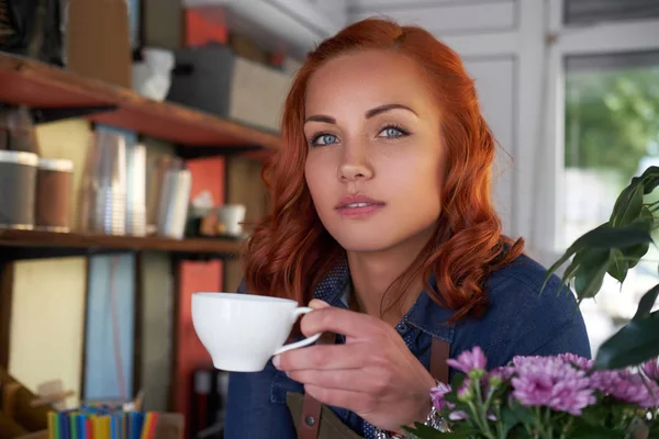 Eine rothaarige Barista trinkt einen Kaffee im Café. — Stockfoto