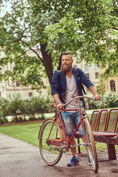 Чоловік одягнений у повсякденний одяг, гуляючи з ретро велосипедом у міському парку . — стокове фото