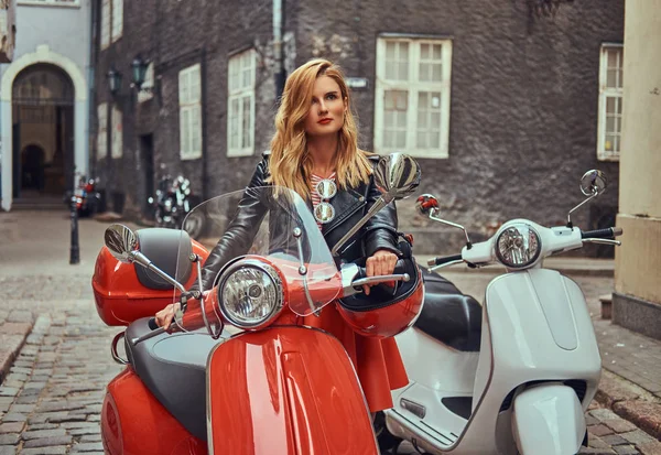 Sexy blonde meisje dragen van stijlvolle kleding, staande op een oude straat met twee retro scooters. — Stockfoto