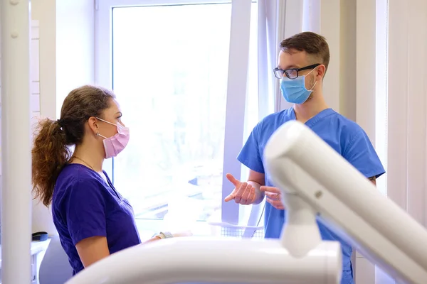 Bonito dentista masculino fala com uma assistente feminina em uma clínica . — Fotografia de Stock