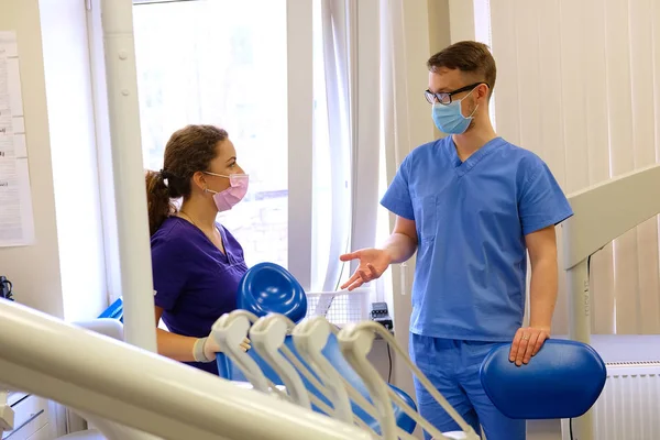 Bonito dentista masculino fala com uma assistente feminina em uma clínica . — Fotografia de Stock