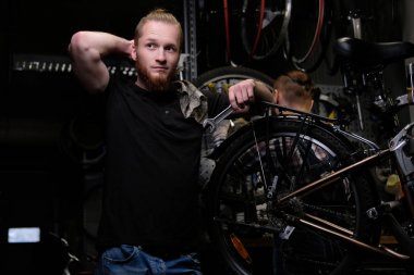  yakışıklı şık erkek bir tamirciye bir bisiklet ile çalışma. İşçi onarmak ve bisiklet bir atölyede bağlar.