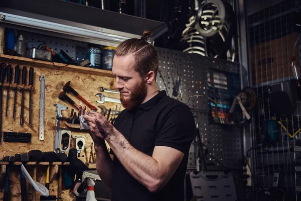 A handsome stylish redhead worker, cleaning his dirty hands after repairing working in a workshop.