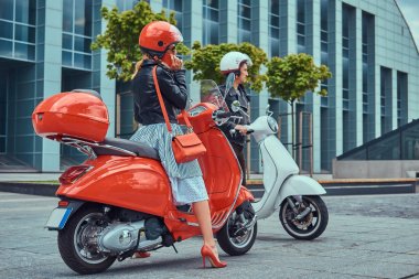Çekici bir romantik çift, yakışıklı ve seksi erkek bir gökdelen karşı retro İtalyan scooter üzerinde oturuyor. Telefonla konuşurken kız süre bekleyen bir adam.