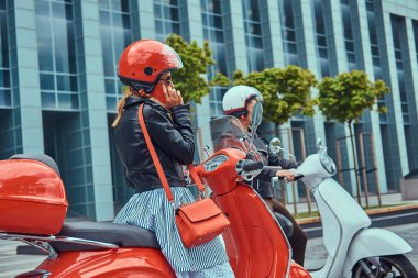 Çekici bir romantik çift, yakışıklı ve seksi erkek bir gökdelen karşı retro İtalyan scooter üzerinde oturuyor. Telefonla konuşurken kız süre bekleyen bir adam.