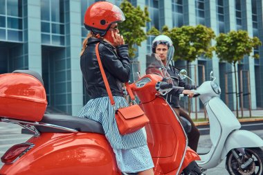 Çekici bir romantik çift, yakışıklı ve seksi erkek bir gökdelen karşı retro İtalyan scooter üzerinde oturuyor. Telefonla konuşurken kız süre bekleyen bir adam.