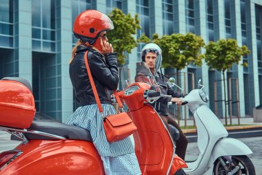 Çekici bir romantik çift, yakışıklı ve seksi erkek bir gökdelen karşı retro İtalyan scooter üzerinde oturuyor. Telefonla konuşurken kız süre bekleyen bir adam.