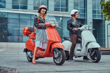 Çekici bir romantik çift, yakışıklı ve seksi erkek, bir gökdelen karşı iki retro İtalyan scooter ile ayakta.