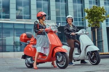 Çekici bir romantik çift, yakışıklı ve seksi erkek, bir gökdelen karşı iki retro İtalyan scooter ile ayakta.