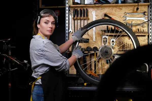 Mulher Bonita Roupas Trabalho Avental Óculos Repara Uma Roda Bicicleta — Fotografia de Stock