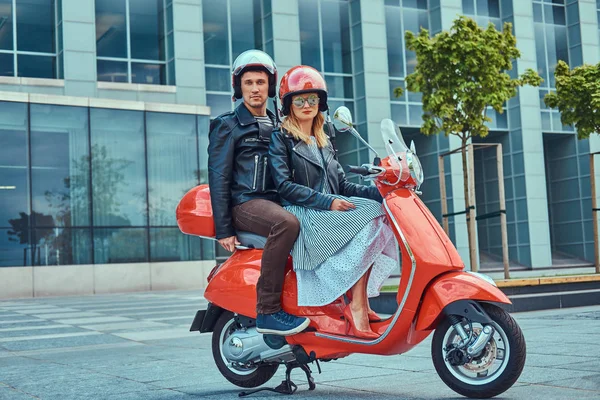 Çekici çift, yakışıklı ve seksi erkek birlikte bir şehirde kırmızı bir retro scooter sürme.