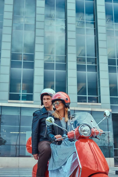 Çekici çift, yakışıklı ve seksi erkek birlikte bir şehirde kırmızı bir retro scooter sürme.