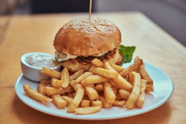 Yakın çekim görüntüsü hamburger patates kızartması ve beyaz tabakta baharatlı sos ile. Sağlıksız yiyecek konsepti.