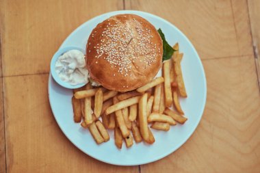 Yakın çekim görüntüsü hamburger patates kızartması ve beyaz tabakta baharatlı sos ile. Sağlıksız yiyecek konsepti.