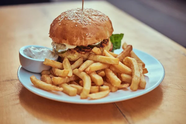 Yakın çekim görüntüsü hamburger patates kızartması ve beyaz tabakta baharatlı sos ile. Sağlıksız yiyecek konsepti.