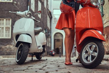 Şık kıyafetlerle iki retro scooter ile eski bir sokakta duran seksi kız.