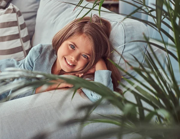 Evde Kanepede Yatan Bir Kameraya Bakarak Mutlu Küçük Bir Kızla — Stok fotoğraf