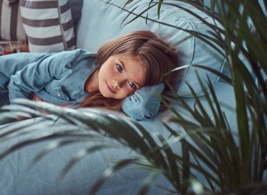 Uzun kahverengi saçlı, piercing ile tatlı bir küçük kız portresi bakışta, yalancı bir kanepe evde yalnız.