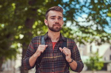 Şehir parkında duran bir Polar gömlek giymiş genç güzel bir öğrenci ile şık saç ve sakal, yakın çekim portresi.