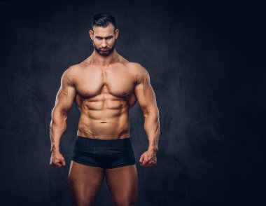 Bir stüdyoda poz bir gömleksiz uzun boylu büyük olmayan erkek bir şık saç ve sakal, iç çamaşırı, kaslı bir vücut portresi. Karanlık bir arka plan üzerinde izole.