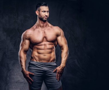 Bir stüdyoda poz bir gömleksiz uzun boylu büyük erkek bir şık saç ve sakal, bir spor şort ile kas gövdeli bir portresi. Karanlık bir arka plan üzerinde izole.